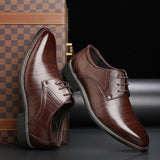 Scarpe eleganti da uomo in pelle marrone lucida, stile derby, su sfondo nero con valigia a scacchi. Calzature formali di lusso.